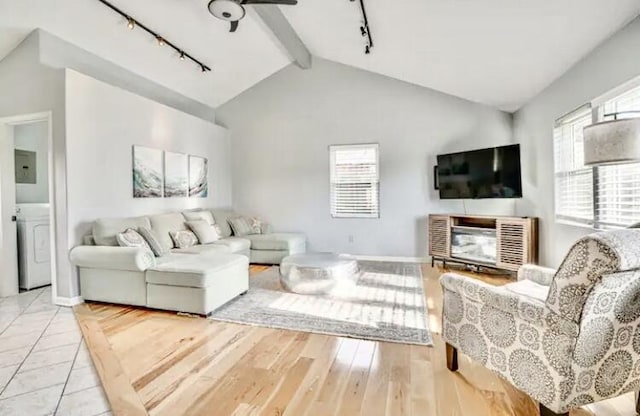 living room with washer / clothes dryer, vaulted ceiling, track lighting, and electric panel