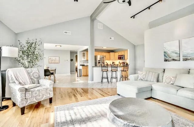 living room featuring light hardwood / wood-style flooring, high vaulted ceiling, and beamed ceiling