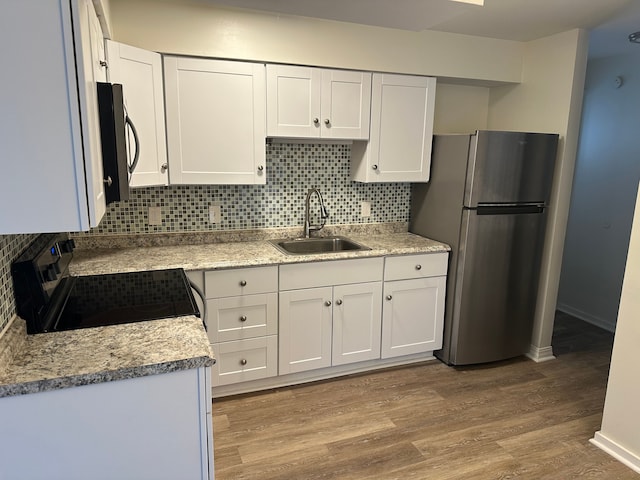 kitchen featuring appliances with stainless steel finishes, white cabinetry, sink, decorative backsplash, and light hardwood / wood-style floors