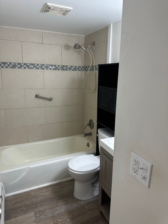 full bathroom with tiled shower / bath, vanity, toilet, and hardwood / wood-style floors