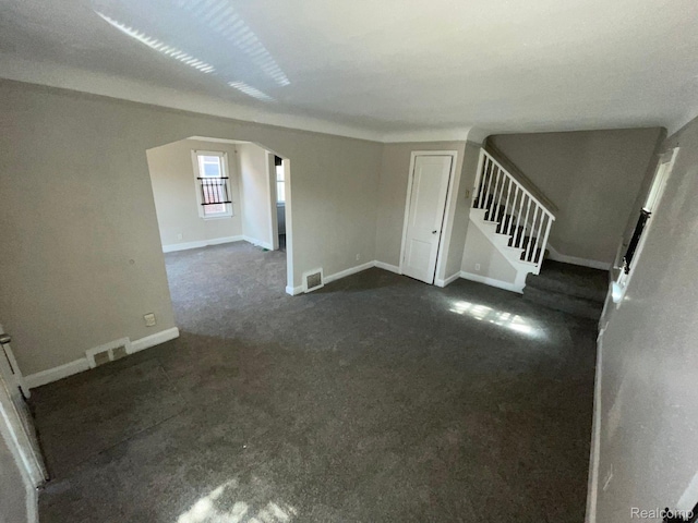 19254 Keystone St, Detroit, MI 48234 - unfurnished living room featuring arched walkways, dark colored carpet, and stairway