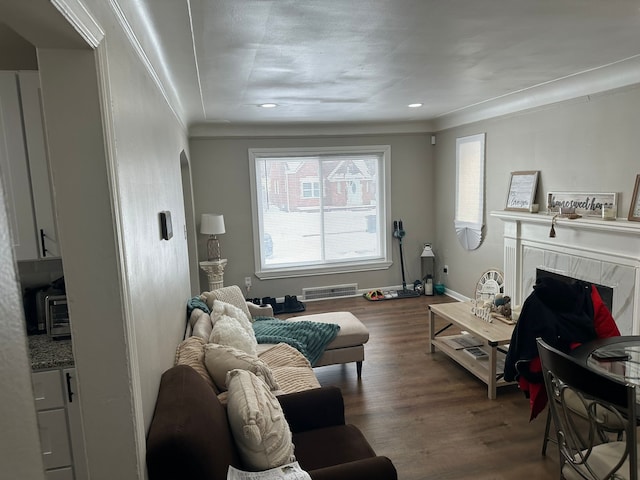 living room with ornamental molding, dark wood-type flooring, and a high end fireplace