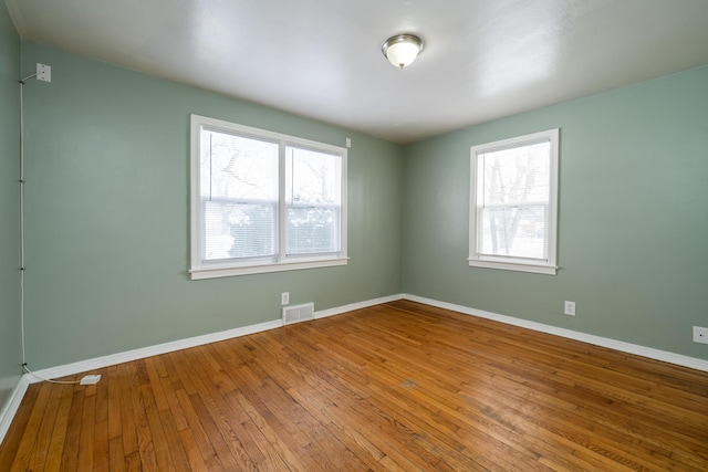 spare room with wood-type flooring and a healthy amount of sunlight