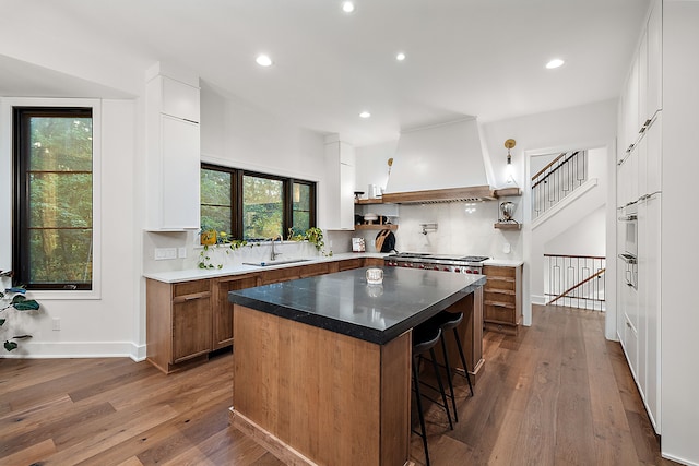 kitchen with tasteful backsplash, sink, a breakfast bar area, a center island, and custom range hood