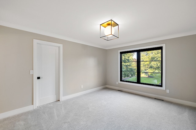 empty room featuring crown molding and light colored carpet