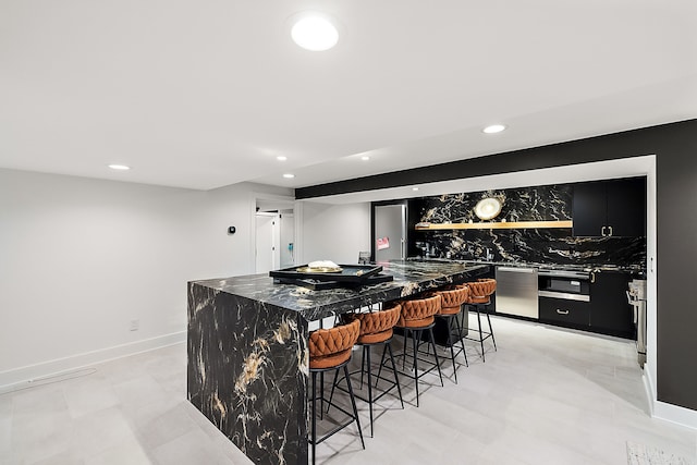 kitchen featuring dark stone counters, a kitchen breakfast bar, dishwasher, and a kitchen island