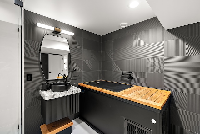 bathroom featuring vanity and tile walls