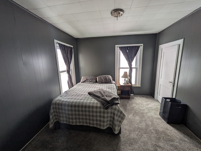 bedroom featuring carpet flooring and wood walls