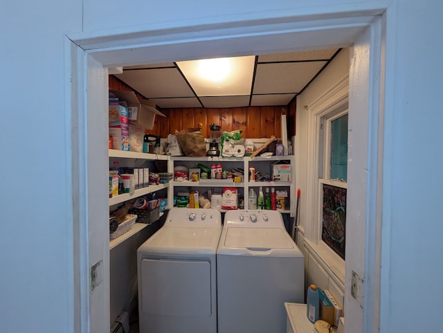 laundry area featuring wooden walls and washing machine and dryer