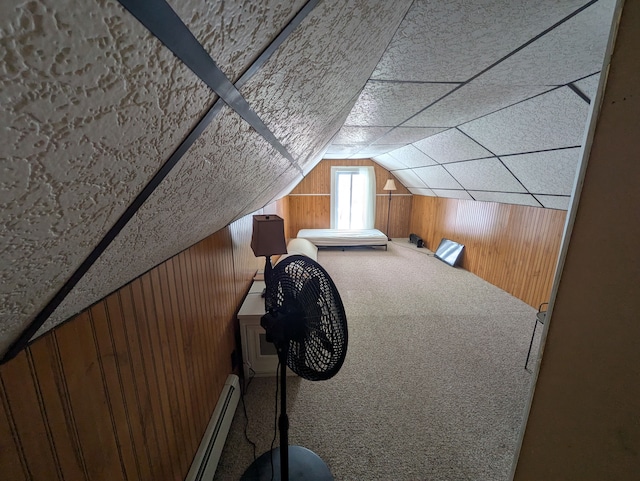 bedroom with carpet floors, vaulted ceiling, wood walls, and baseboard heating