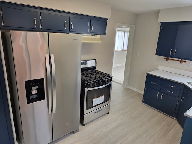 kitchen with blue cabinetry, stainless steel appliances, and light hardwood / wood-style floors