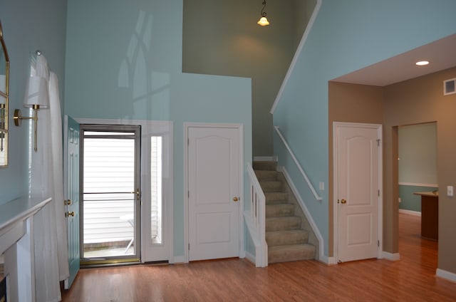 foyer entrance with a towering ceiling and light hardwood / wood-style floors