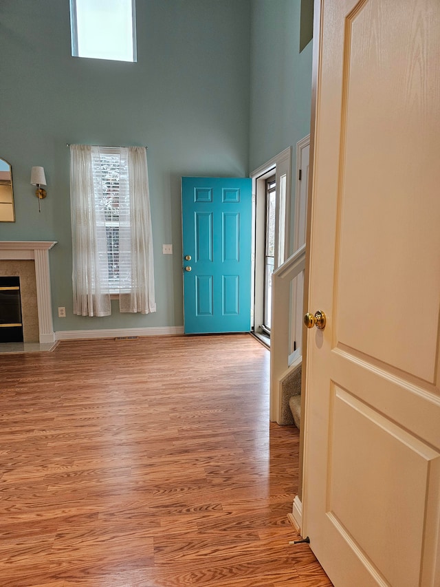 foyer featuring a fireplace, light hardwood / wood-style flooring, and a high ceiling