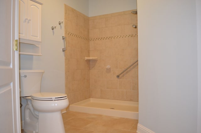 bathroom featuring toilet, tile patterned flooring, and a tile shower