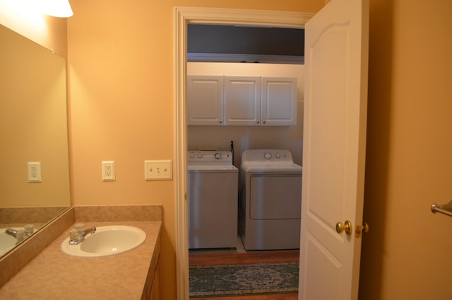 washroom with cabinets, washing machine and dryer, and sink