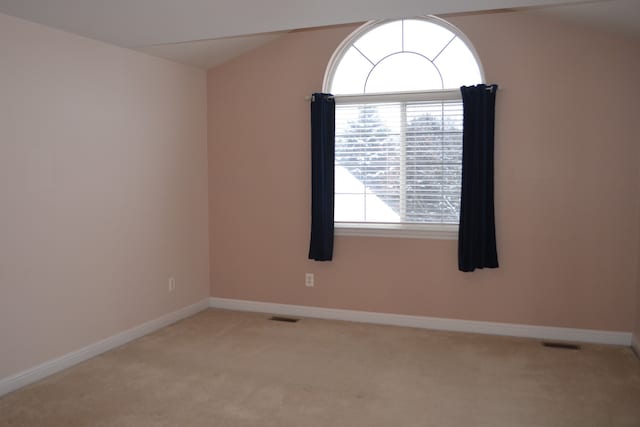 carpeted spare room with vaulted ceiling