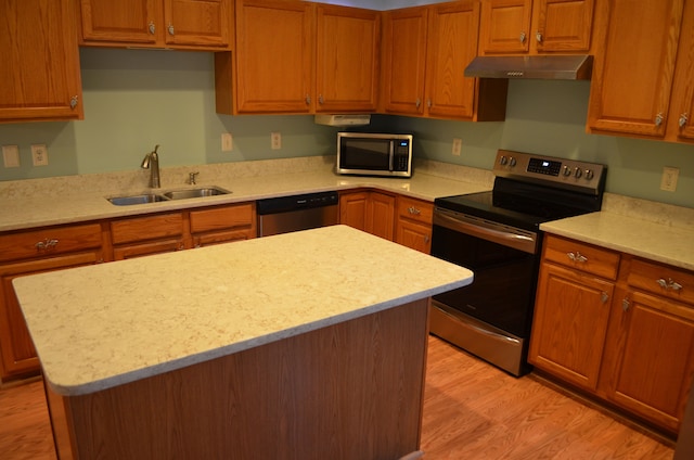 kitchen featuring sink, light stone counters, appliances with stainless steel finishes, a kitchen island, and light hardwood / wood-style floors