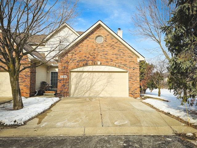 view of front of house with concrete driveway, a garage, brick siding, and a chimney