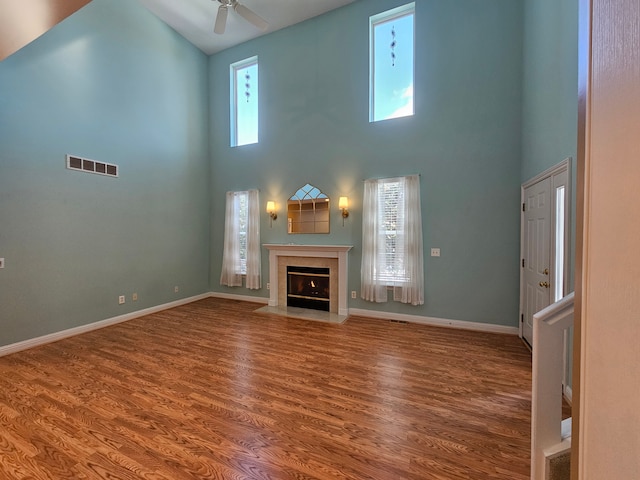 unfurnished living room featuring a fireplace with flush hearth, wood finished floors, visible vents, and a wealth of natural light