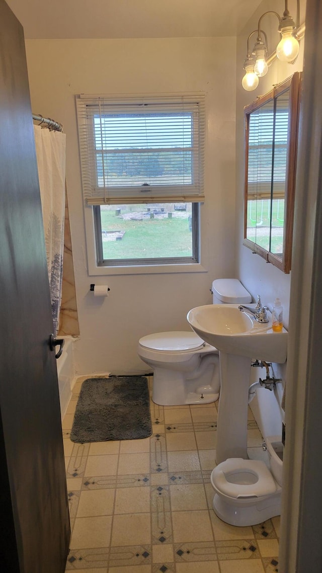 bathroom with a notable chandelier, a wealth of natural light, shower / bath combination with curtain, and toilet