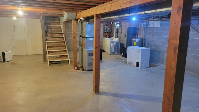 basement featuring water heater, fridge, and independent washer and dryer