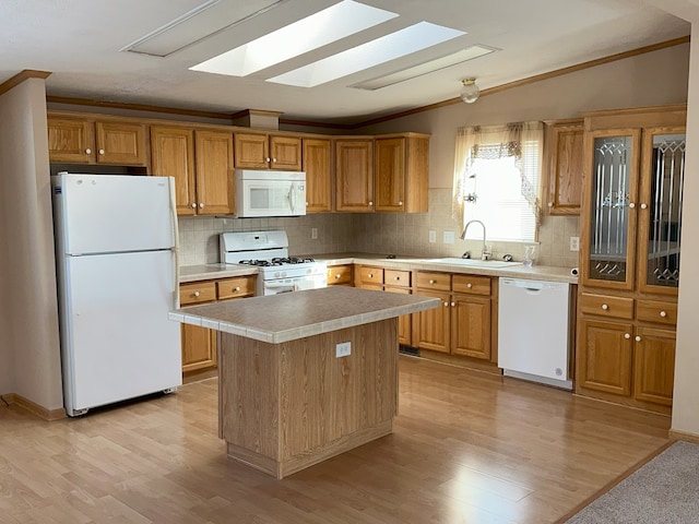 kitchen featuring sink, white appliances, lofted ceiling with skylight, a center island, and light hardwood / wood-style floors