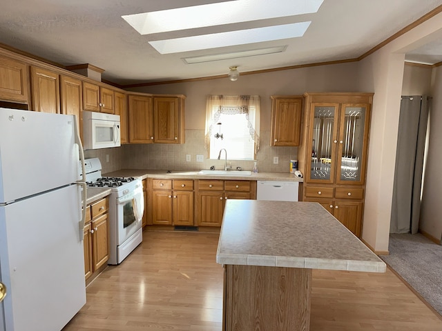 kitchen featuring sink, white appliances, a center island, vaulted ceiling with skylight, and tasteful backsplash