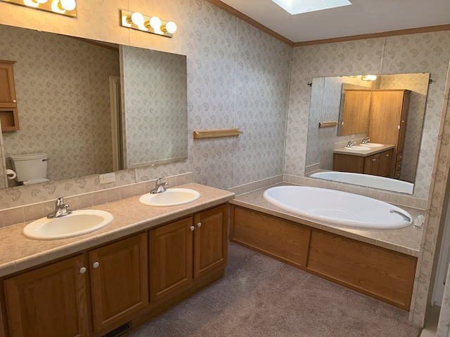 bathroom featuring toilet, crown molding, a skylight, vanity, and a bathing tub