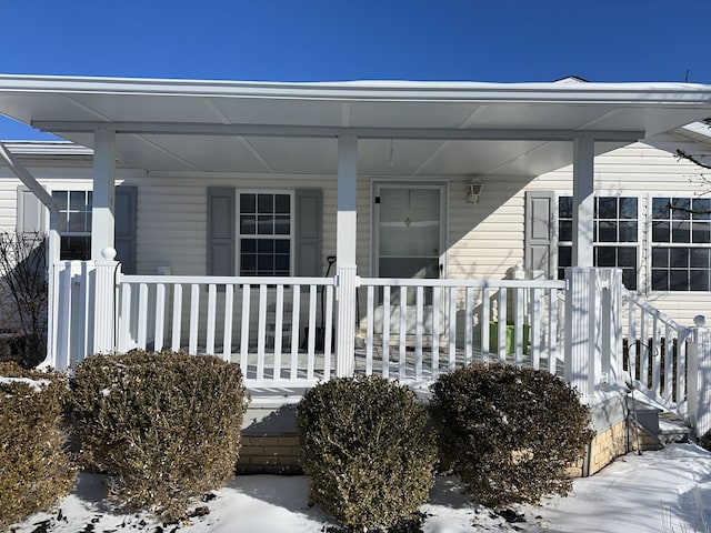 snow covered property entrance with a porch