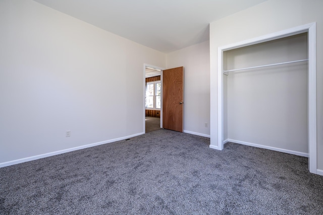 unfurnished bedroom with dark carpet and a closet