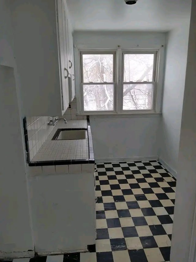 kitchen featuring white cabinetry, sink, and tile countertops