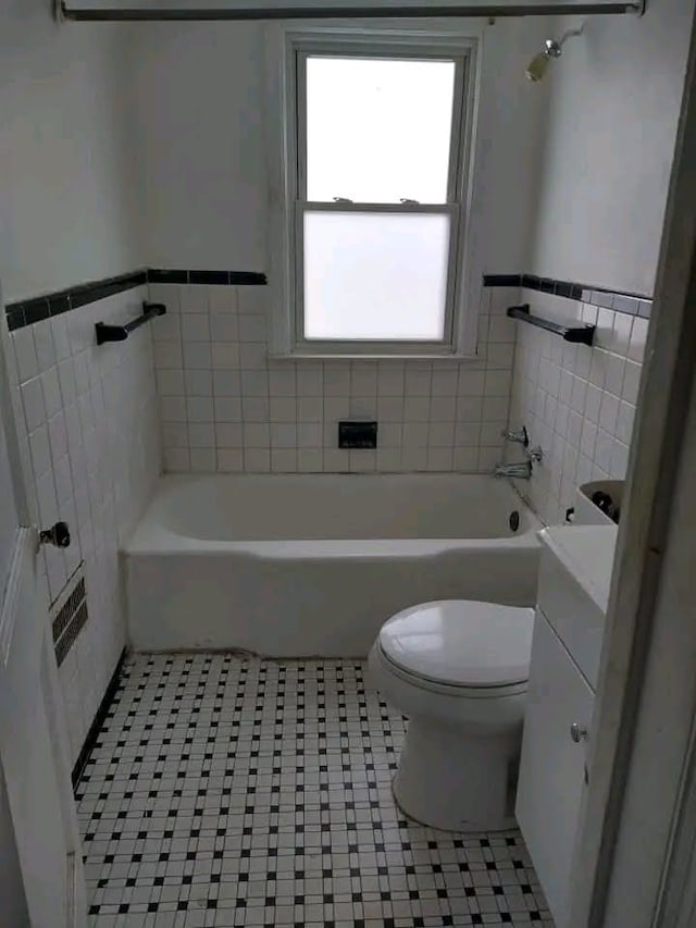 bathroom with tile patterned flooring, a tub to relax in, tile walls, and toilet