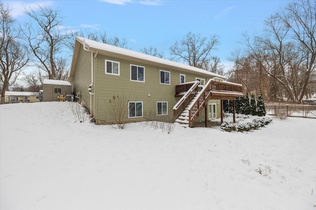 snow covered property with cooling unit, a deck, and a shed