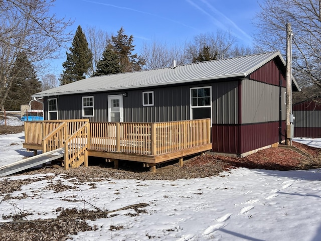 snow covered back of property with a deck