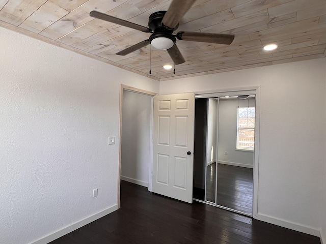 unfurnished bedroom featuring dark hardwood / wood-style flooring, wood ceiling, a closet, and ceiling fan