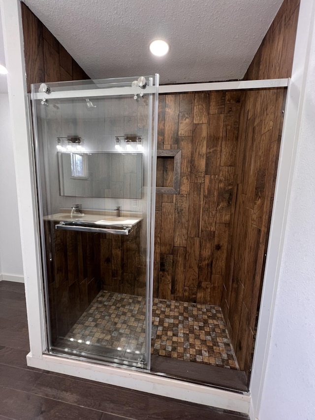 bathroom with a shower with shower door and a textured ceiling