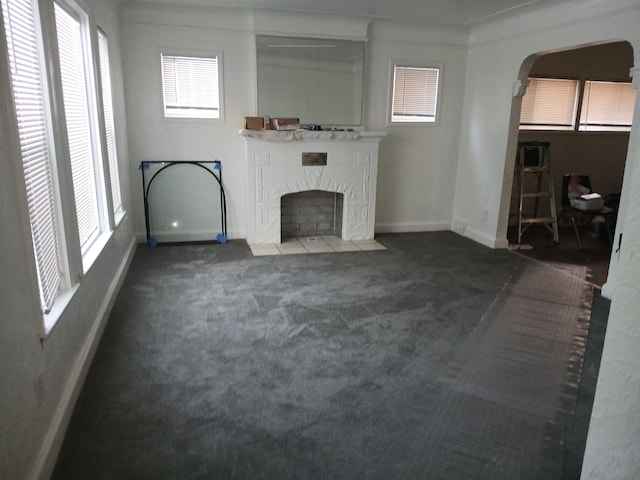 unfurnished living room with dark colored carpet and plenty of natural light