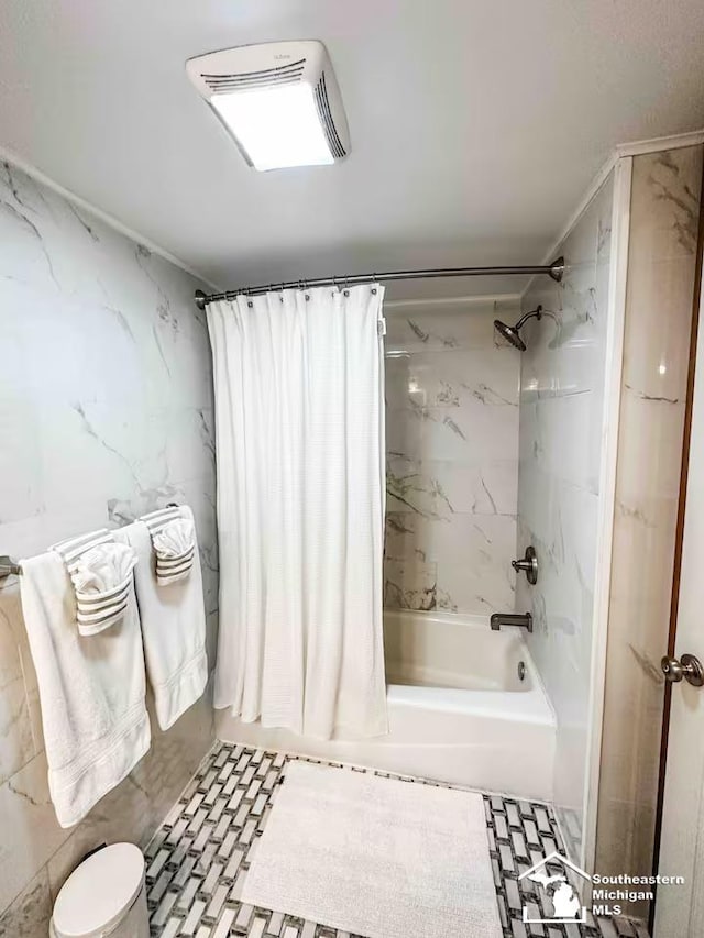 bathroom with tile walls and shower / bath combo