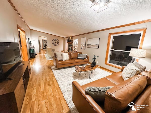 living room with ornamental molding, a textured ceiling, and light hardwood / wood-style flooring