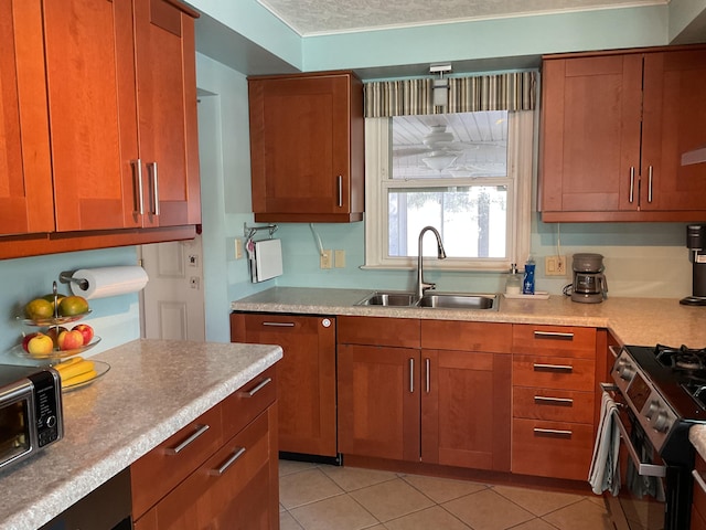 kitchen featuring light tile patterned flooring, sink, stainless steel stove, and a textured ceiling