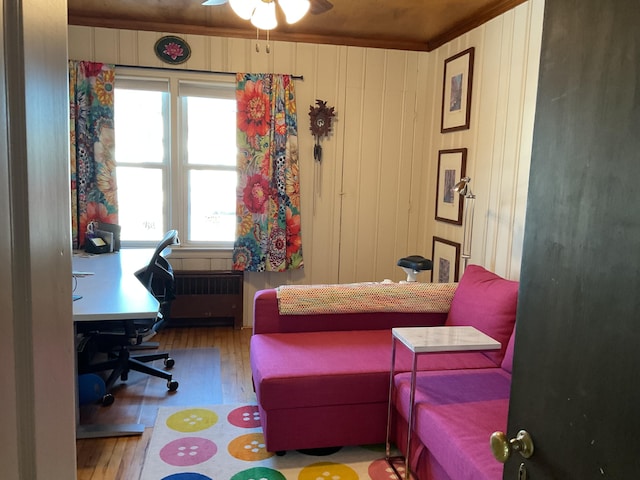 bedroom with radiator heating unit, wooden walls, hardwood / wood-style floors, and multiple windows