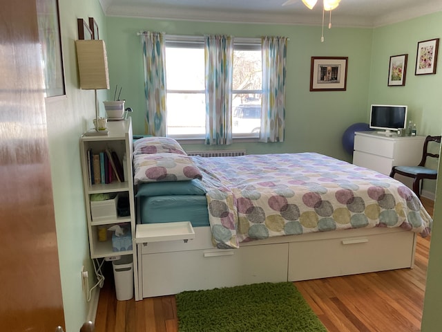 bedroom with ornamental molding, radiator heating unit, ceiling fan, and light hardwood / wood-style flooring