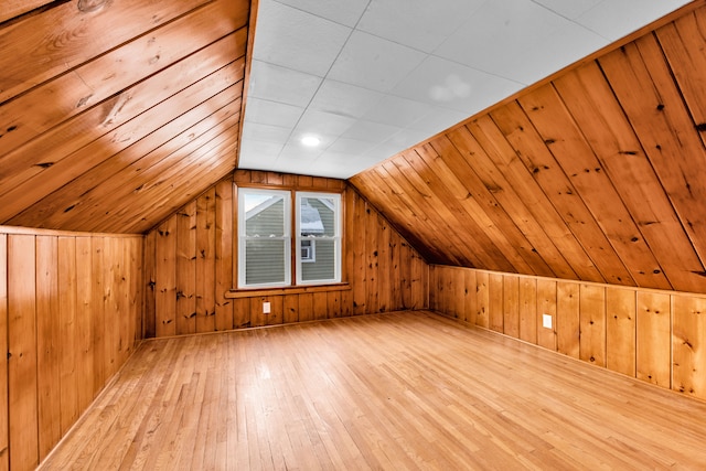 bonus room featuring vaulted ceiling, light wood-type flooring, and wood walls