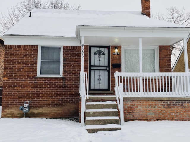 snow covered property entrance featuring covered porch