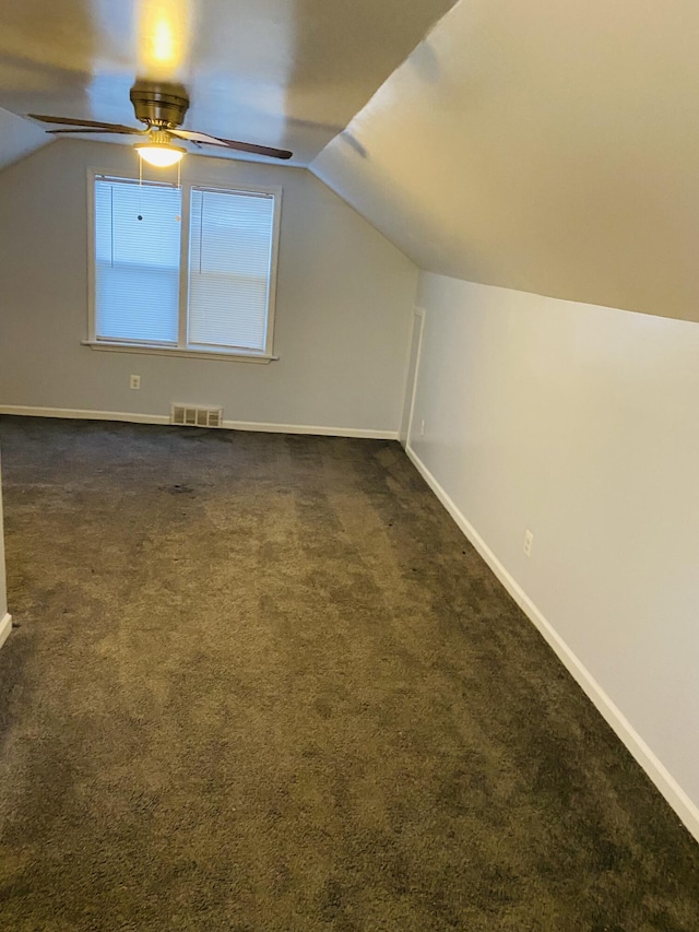 additional living space with ceiling fan, vaulted ceiling, and dark colored carpet