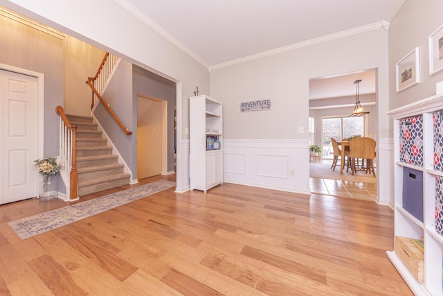 entrance foyer with ornamental molding and light hardwood / wood-style flooring