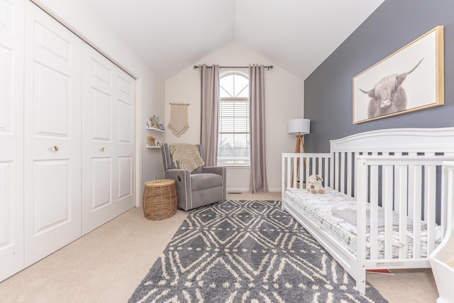 carpeted bedroom featuring lofted ceiling, a crib, and a closet