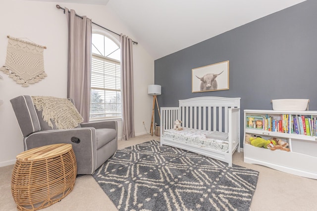 carpeted bedroom featuring vaulted ceiling and a nursery area