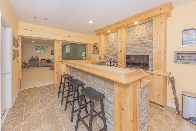 kitchen with decorative columns, wood counters, light brown cabinetry, and a kitchen bar