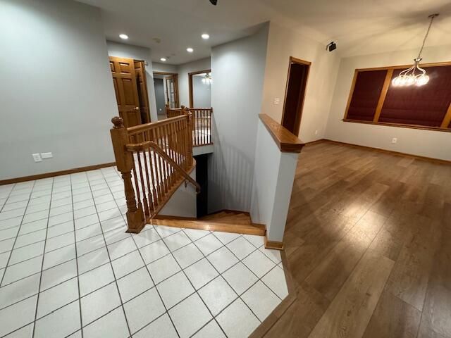 staircase featuring wood-type flooring and a notable chandelier